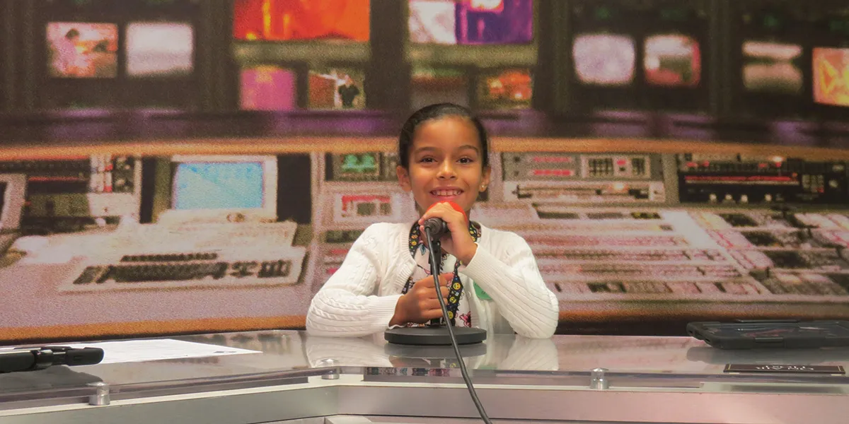 A JA BizTown student smiling at the news-desk station
